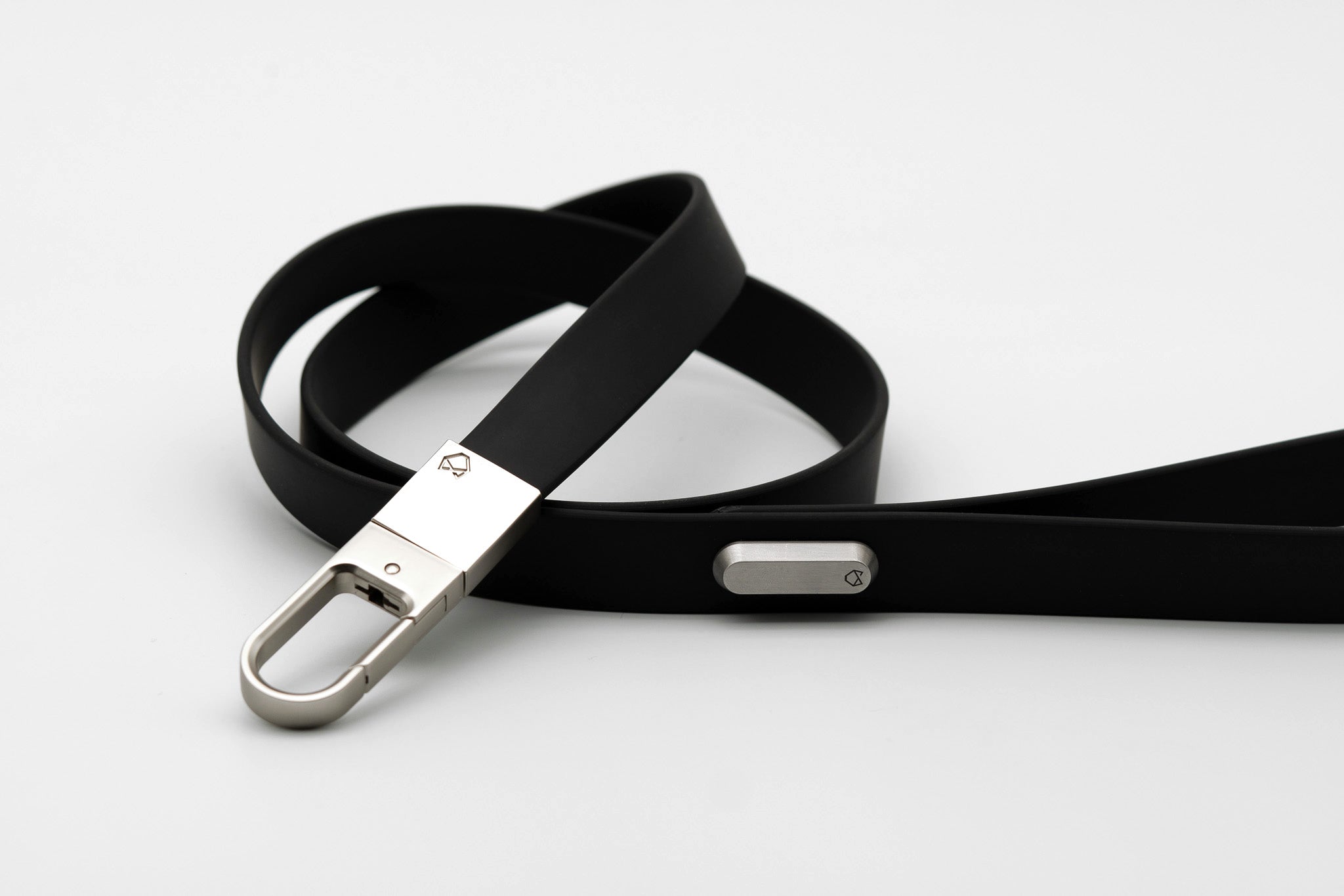Little Lupo Leash L4 coiled on a white surface, emphasizing its compact form, flexible silicone-coated tactical nylon webbing, and the secure stainless steel clip. 