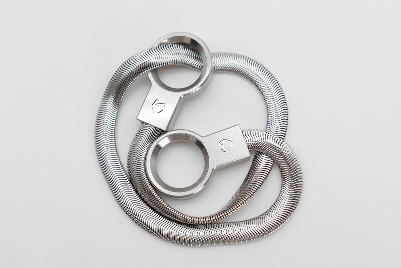 Little Lupo Subtle Strength Collar coiled on a white surface, revealing its compact form and the fluid malleability of its high-quality stainless steel construction.