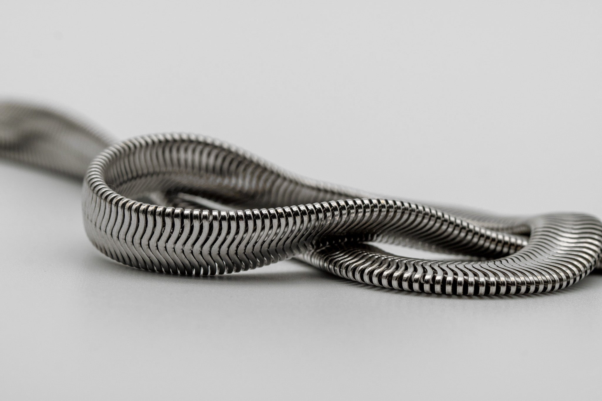 Close-up of the smooth, reflective snake chain from the Subtle Strength collection, highlighting its sleek, modern texture and fluid design.